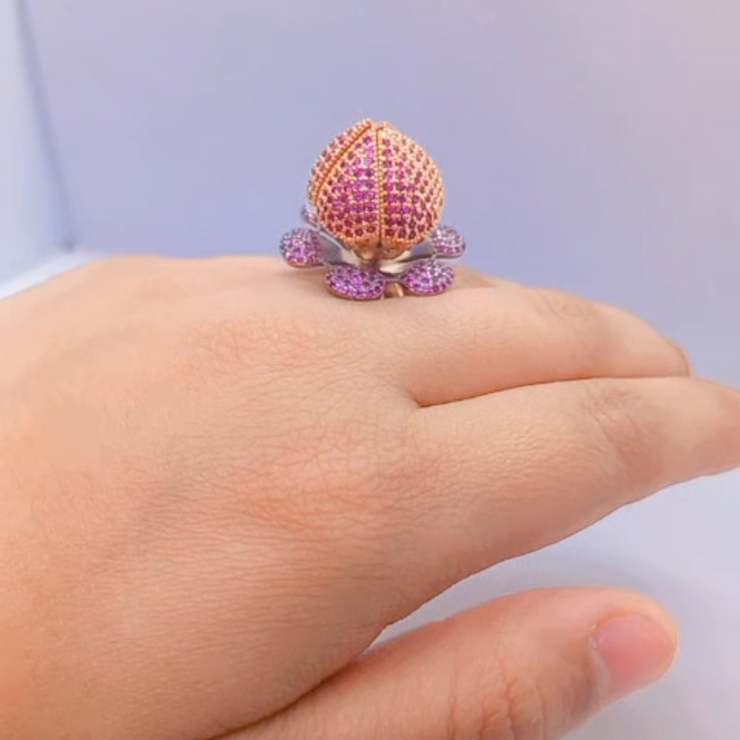 Womenโs lotus blossom statement ring with gold plating, purple crystals, and central gemstone.