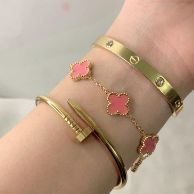 Cartier-inspired bangle, a pink flower charm bracelet, and a sleek gold cuff.