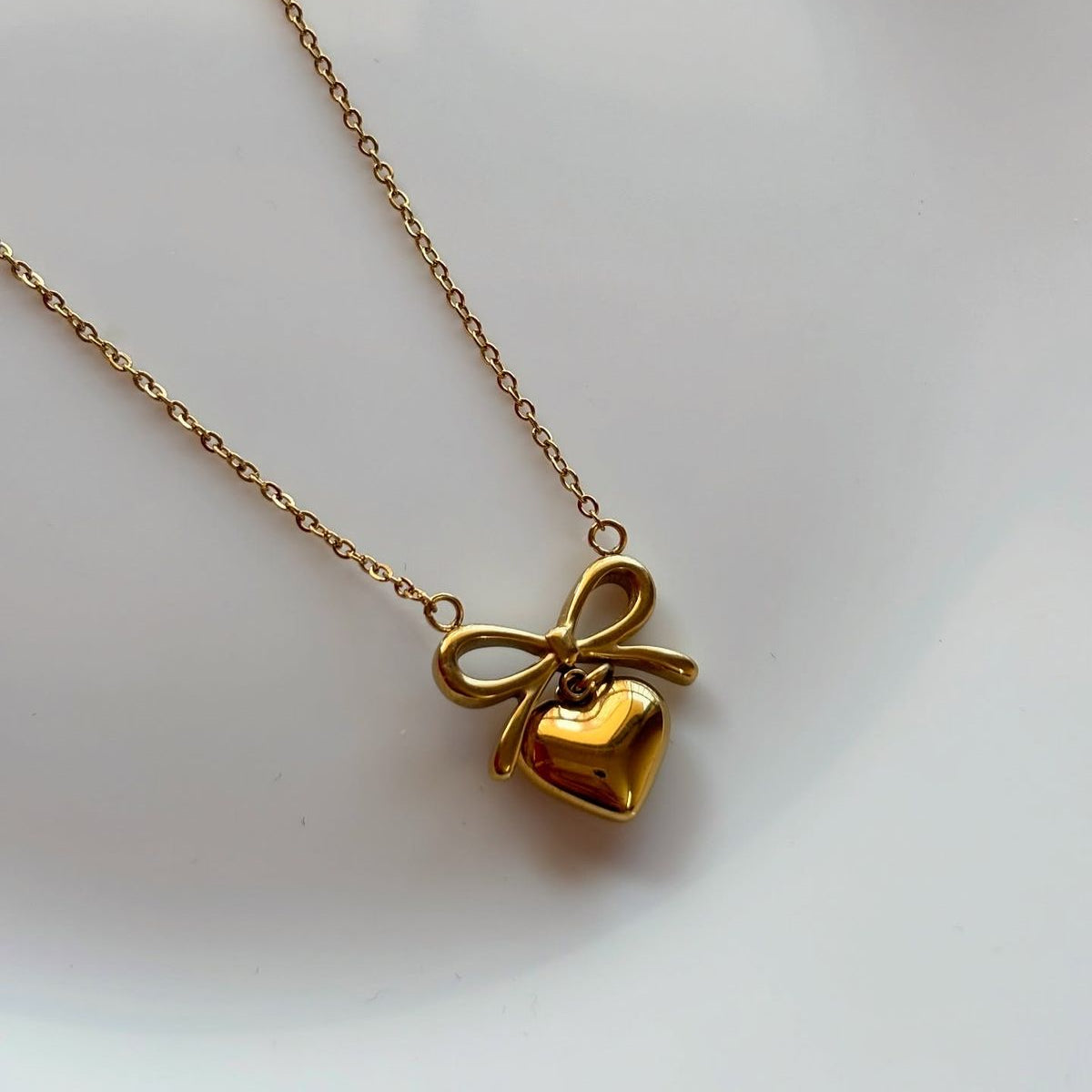 Gold bow heart pendant necklace, elegant non-tarnish jewelry.