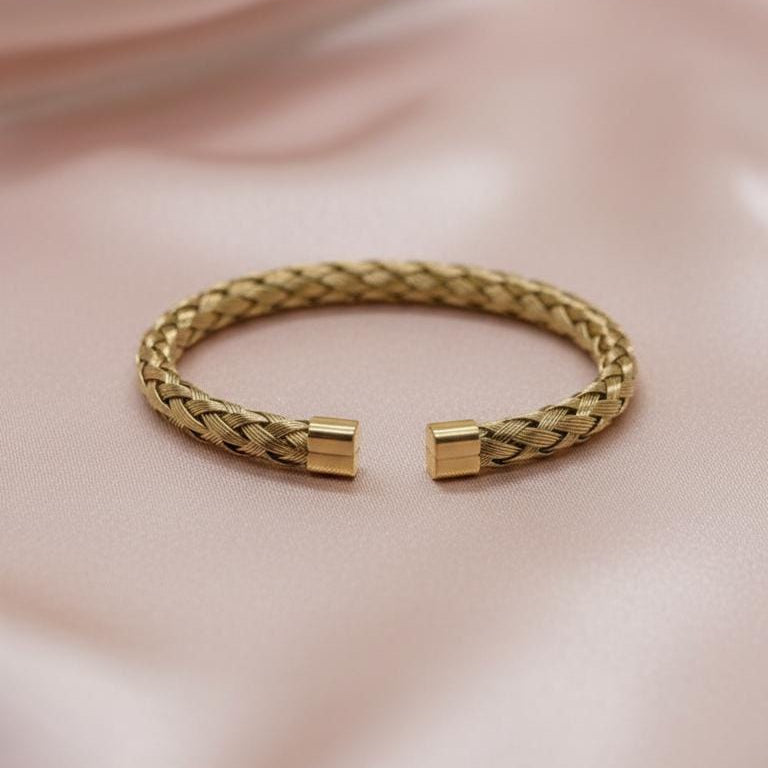 The surface of the bracelet features an intricate braided or woven texture, and the ends are finished with clean, flat gold-tone caps.