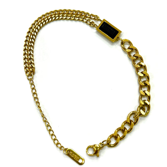 The bracelet features a modern, asymmetrical design: one side is a thick, bold curb chain, while the other is a delicate, fine double-strand chain. Both chains connect to a central, horizontal rectangular charm with a polished black inlay