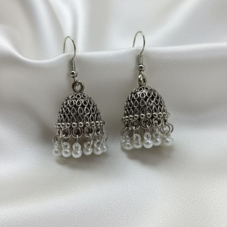 The earrings feature a delicate filigree metalwork pattern on the dome and a fringe of small, white faux-pearl beads dangling from the bottom rim. They hang from simple silver-tone fish-hook ear wires