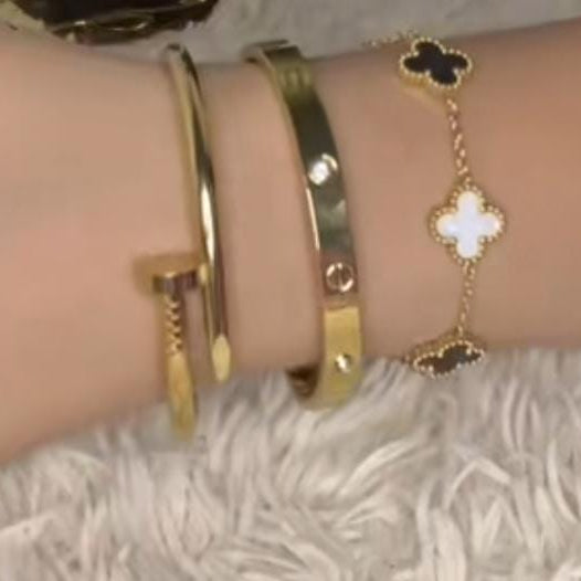a nail-design cuff, a screw-accented bangle with clear crystals, and a chain bracelet with black and white quatrefoil (clover) charms.