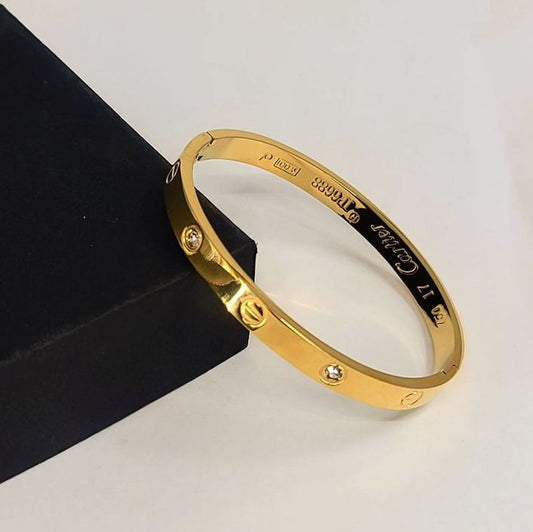 Cartier handcuff bangle with embossed detailing, non-tarnish finish.