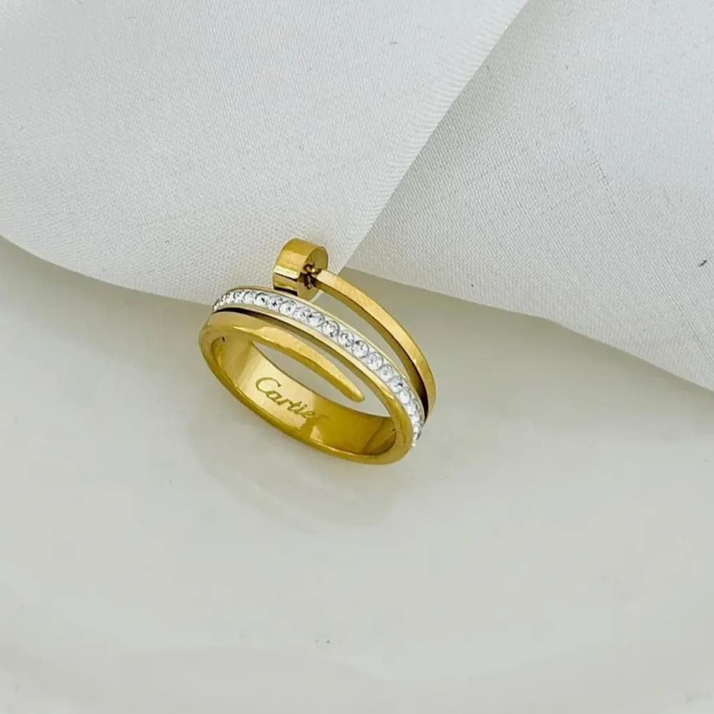 Gold-plated Cartier ring with sparkling stones, featuring a twist design, displayed on a white surface.