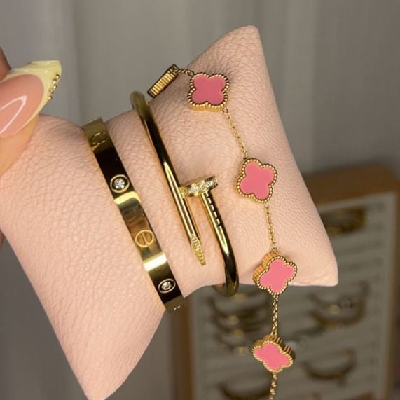 Cartier-inspired bangle, a pink flower charm bracelet, and a sleek gold cuff.