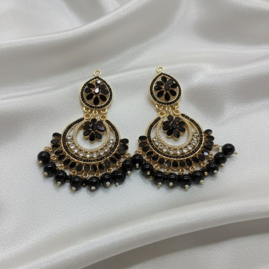 The earrings are black and gold-tone, featuring a black floral stud, a large crescent-shaped body set with an inner row of white rhinestones and a central black flower, and a full fringe of dangling, polished black beads.