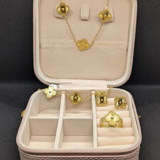 A 3-piece set of gold-toned jewelry featuring an ornate, ridged four-petal (clover) motif, including a necklace, a charm bracelet, and a matching ring. The set is displayed in an open pink travel jewelry box, emphasizing the waterproof and 70% off sale.