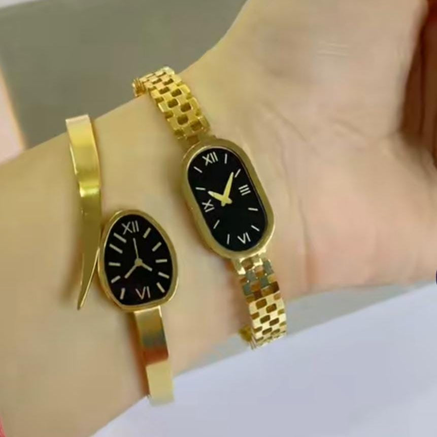 The main watch has a black oval dial with Roman numerals (XII and VI) on a gold link band. The thinner bracelet has a smaller, similar black oval accent.