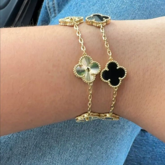Gold clover bracelet with black enamel charms on wrist