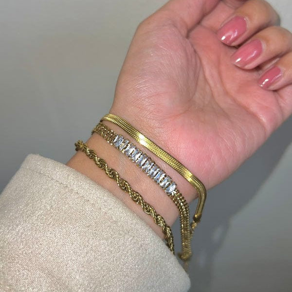 “Elegant 3-piece gold bracelet set with rope, crystal, and snake chain designs on wrist”