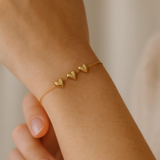 Gold bracelet with three heart charms on adjustable chain