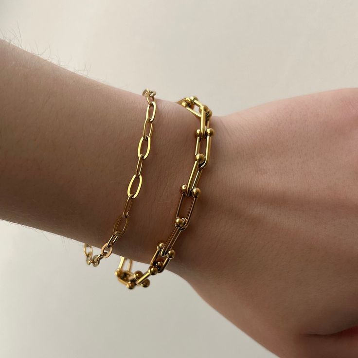 Two layered gold chain bracelets: a thin paperclip chain and a thicker U-link chain with beaded details