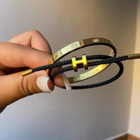 A gold stainless steel bangle and a black braided rope bracelet with gold accents