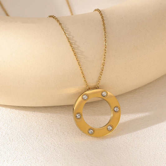Gold circle pendant necklace with embedded crystals on a delicate gold chain