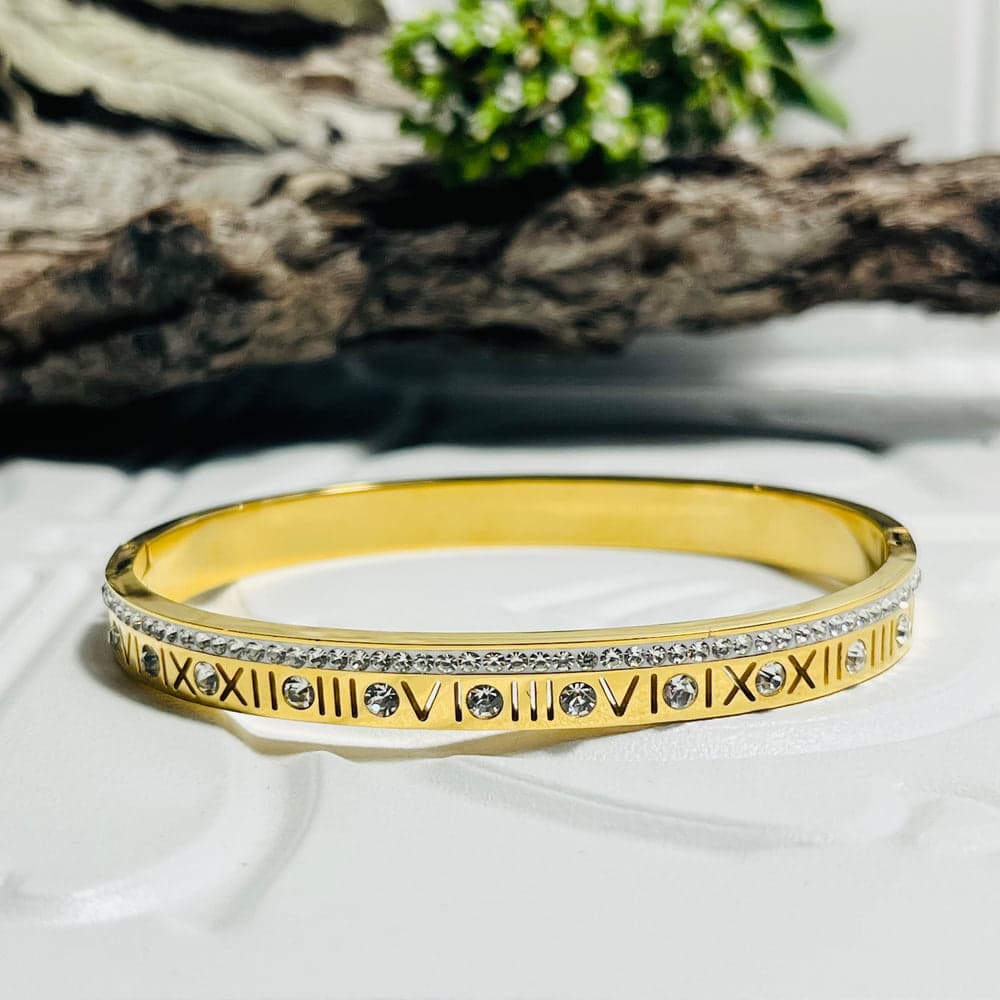 Gold-plated bangle with Roman numeral engravings and sparkling stones.