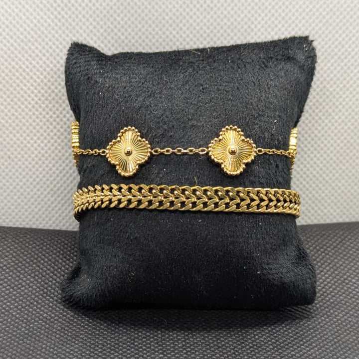 The set includes one delicate chain with two textured, flower-like clover charms, and one thicker classic curb chain bracelet.